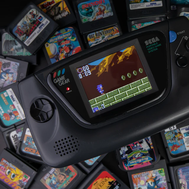 Sega Game Gear handheld with a pile of games